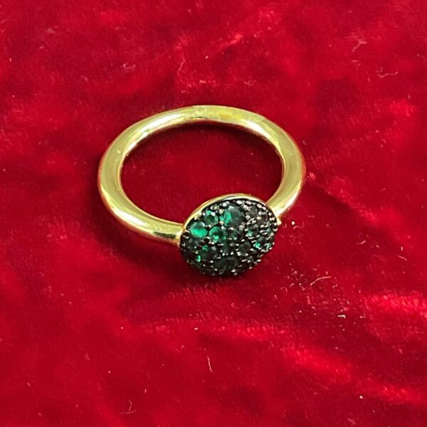 Close-up of a green stone cluster ring on a red background.