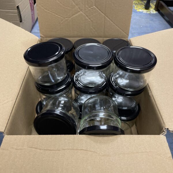 Box of 24 small glass preserve jars with lids.