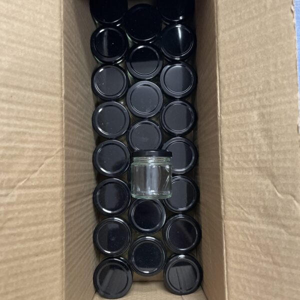 Box of miniature glass preserve jars with lids.