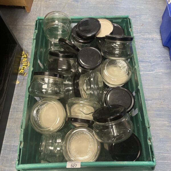 Tray of assorted vintage lidded glass jars for storage.