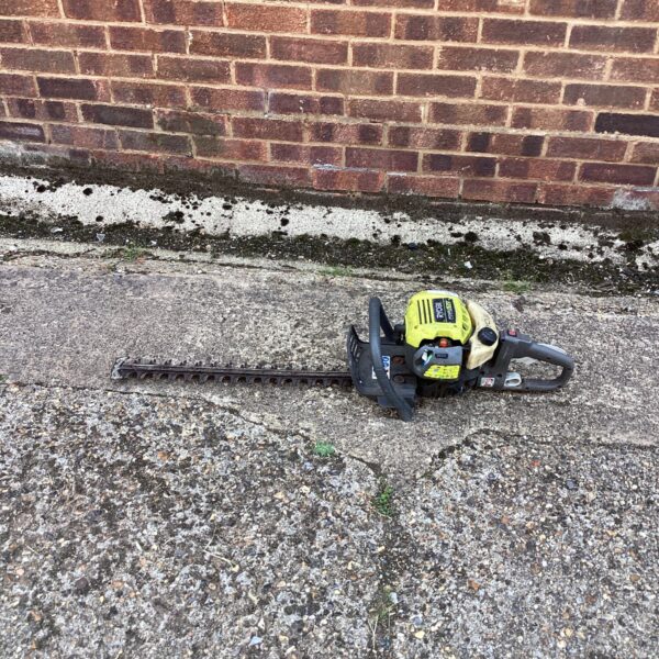 Side view of a used Ryobi hedge cutter garden tool.