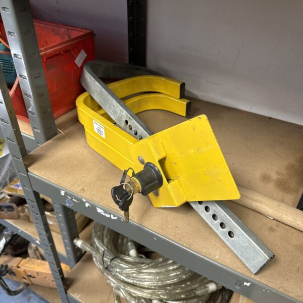 Yellow caravan wheel clamp with keys for trailer security.