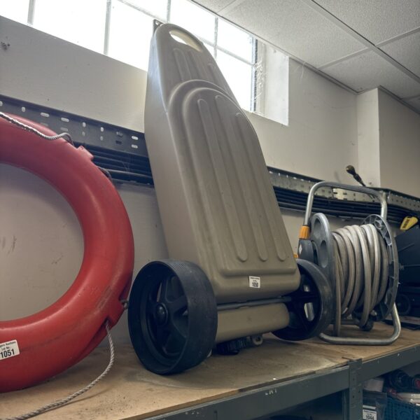 Side view of a grey plastic caravan waste carrier with a wheel.