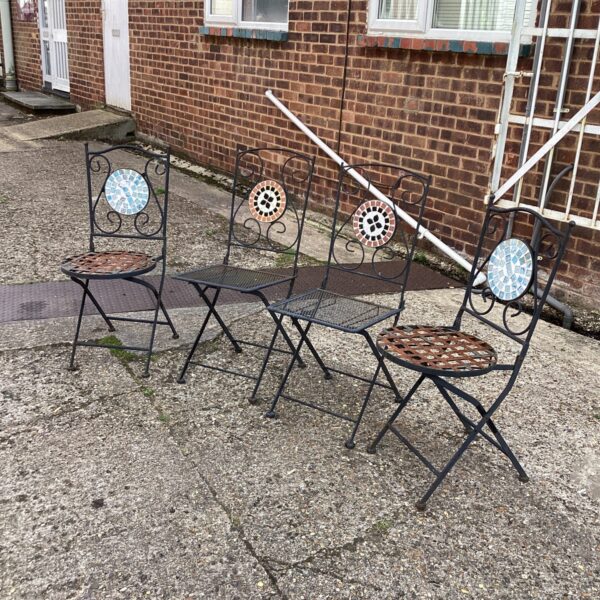 Four vintage metal folding garden chairs in a garden setting.