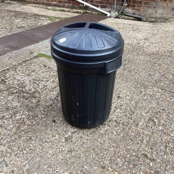 Dark plastic garden bin for outdoor waste storage.