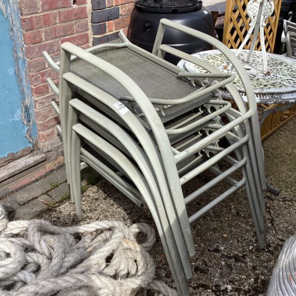 Four metal folding garden chairs in a garden setting.
