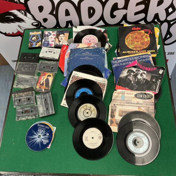 Overview of a mixed lot of 7” vinyl records and cassette tapes.