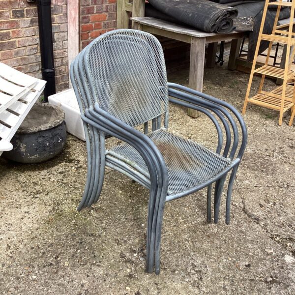 Vintage metal garden chairs stacked outdoors, ideal for patio seating.