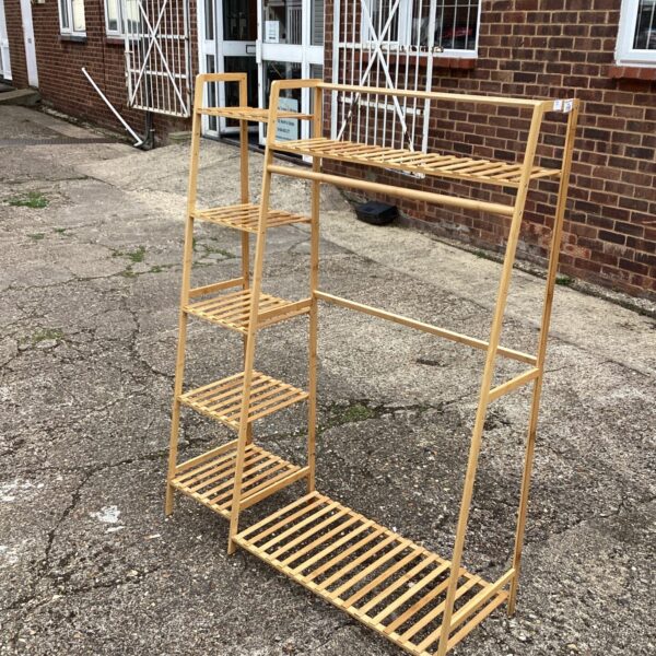 Freestanding wooden clothes rack in a bedroom setting.