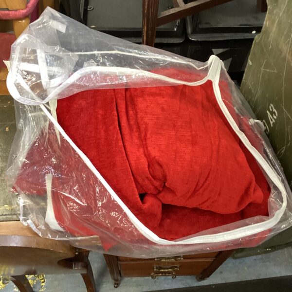 A set of vibrant red curtains stored in plastic.