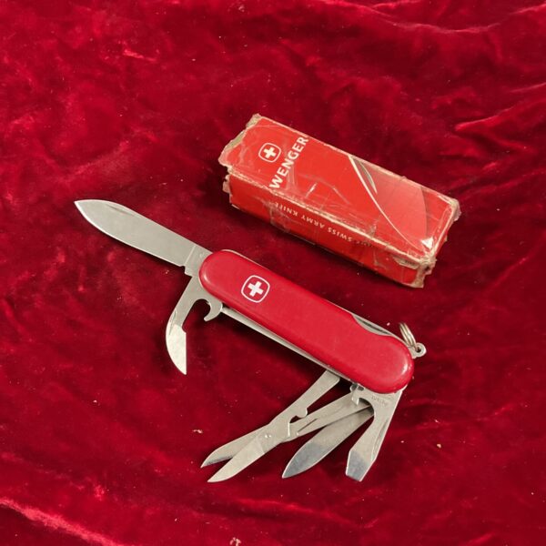Red handled vintage Wenger Swiss Army knife with multiple tools.
