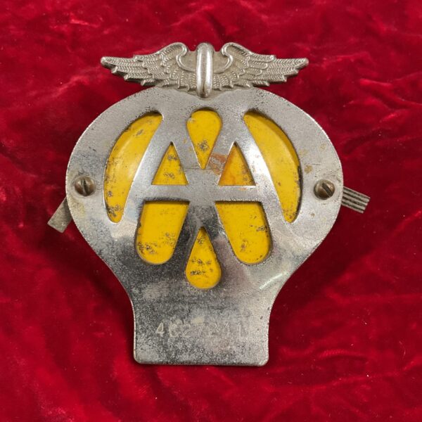 Vintage car grille badge with Art Deco design and chrome finish.