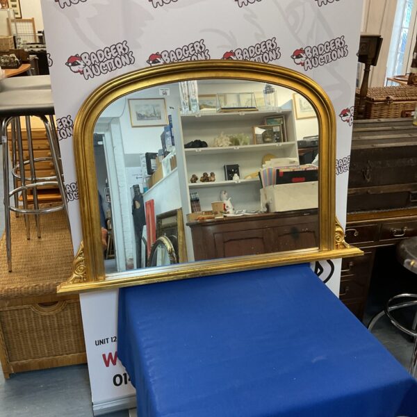 Ornate antique gilded overmantle mirror with detailed frame.