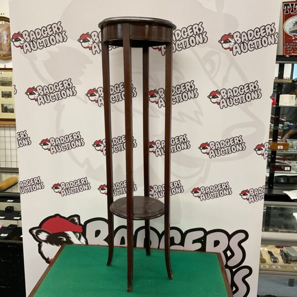Antique mahogany plant stand displayed in front of a backdrop.