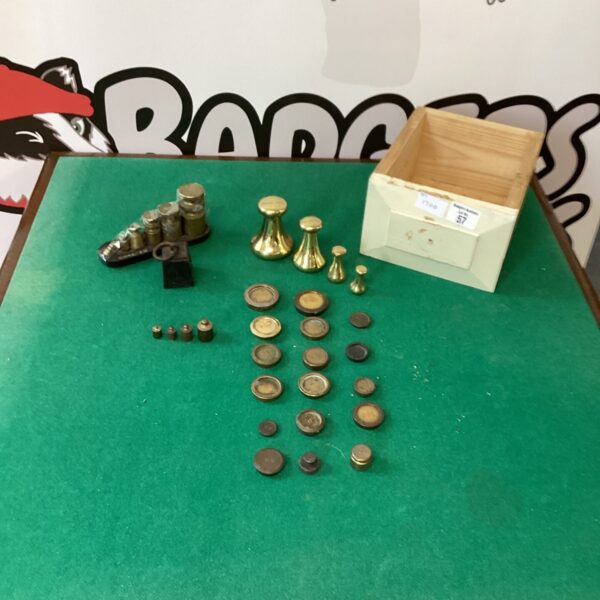Vintage brass kitchen weights on a white surface.