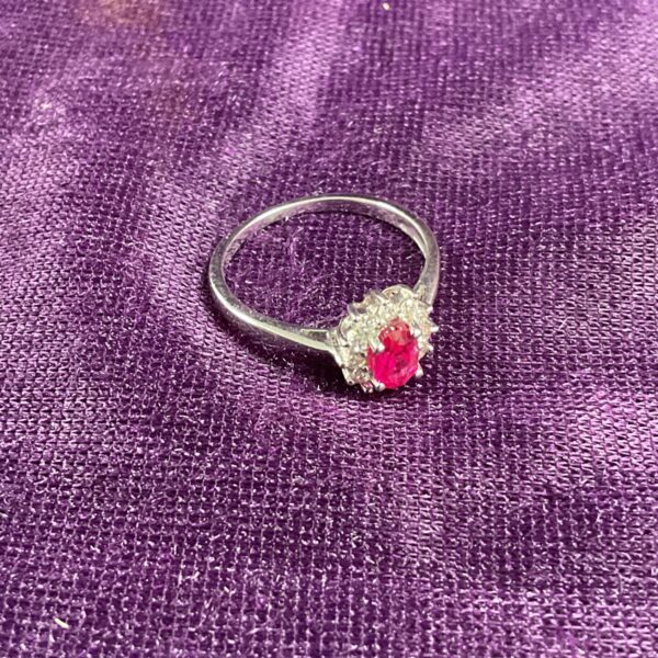 Silver ring with red stone and cubic zirconia halo.