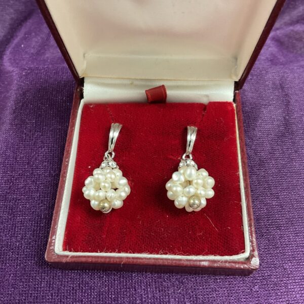 Vintage silver seed pearl cluster earrings on display.