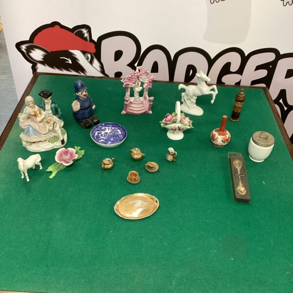 Mixed lot of vintage trinkets and ornaments on a green surface.