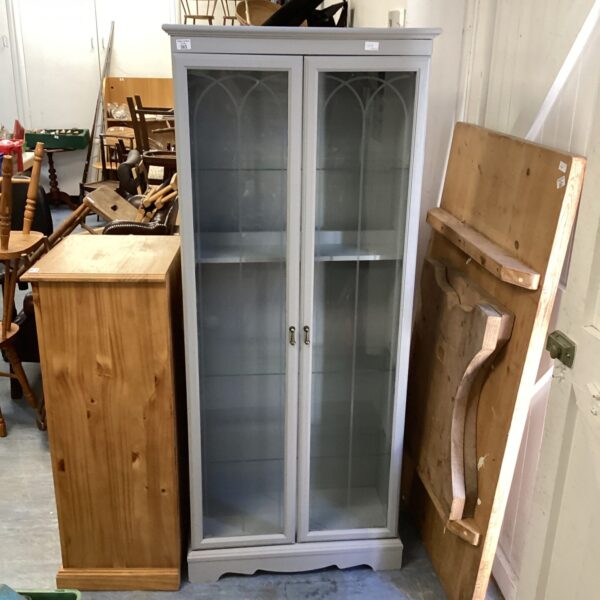Vintage grey display cabinet with glass front for collectibles.
