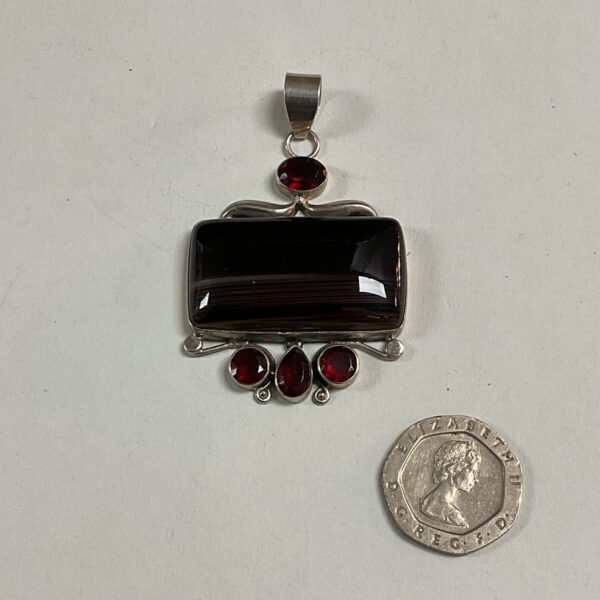 Silver pendant with large banded agate and red stone accent.