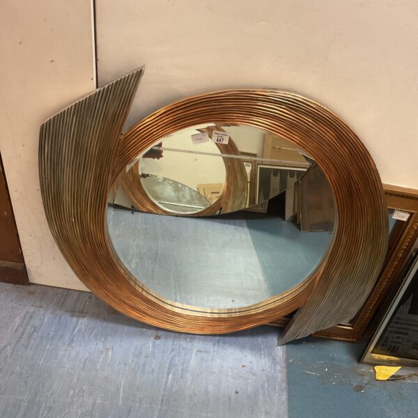 Circular mid-century modern mirror with a swirl pattern.