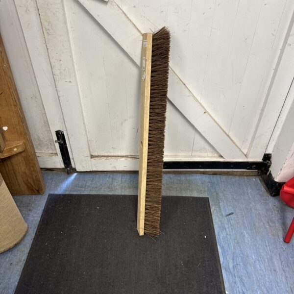 New large broom head with stiff bristles for cleaning floors.