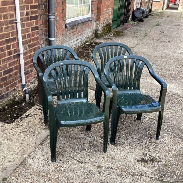 Four brown plastic garden chairs in a garden setting.