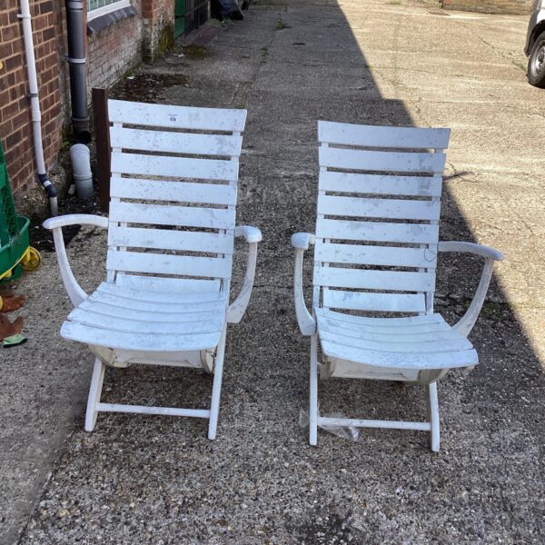 Pair of vintage white garden chairs in a garden setting.