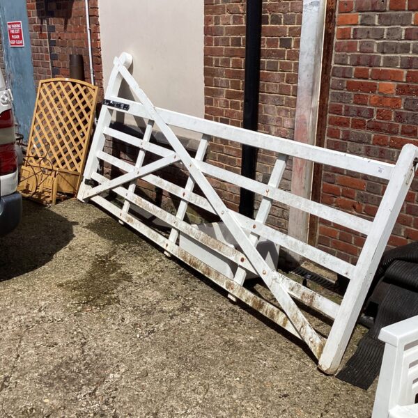 White five-bar wooden gate in a garden setting.