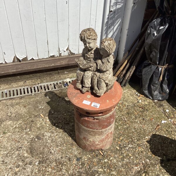 Vintage terracotta chimney pot with a detailed garden ornament.