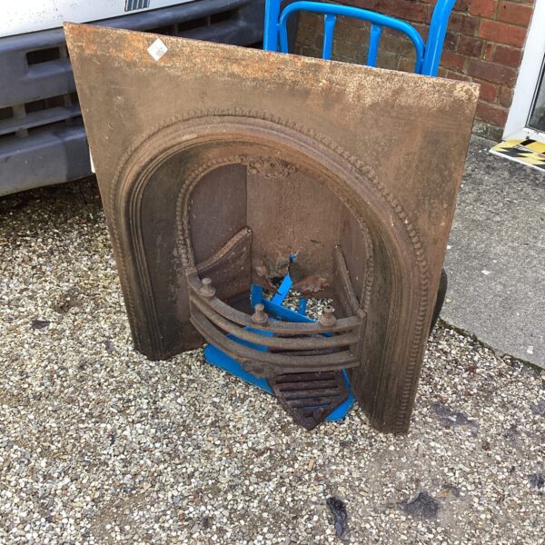 Antique wrought iron fireplace with decorative grate and arched design.