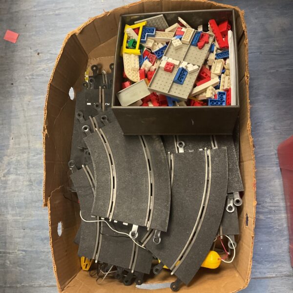 Scalextric track and Lego pieces in a cardboard box.