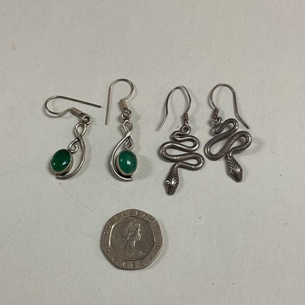 Vintage silver snake earrings with a green stone detail.