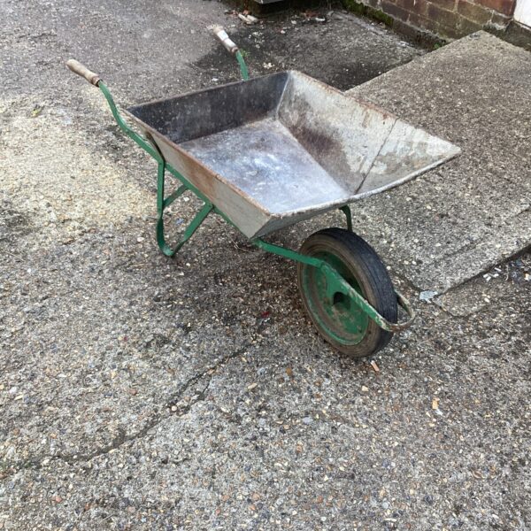 Vintage galvanised wheelbarrow in a garden setting.