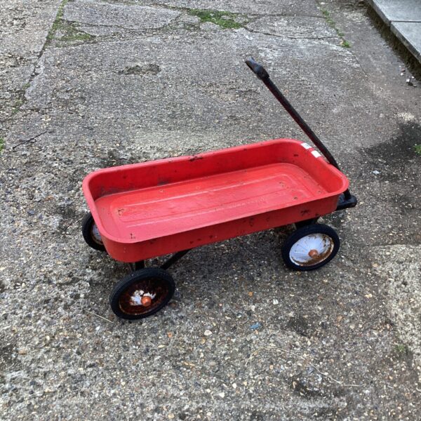 Red metal garden barrow with a single wheel, showing signs of age.