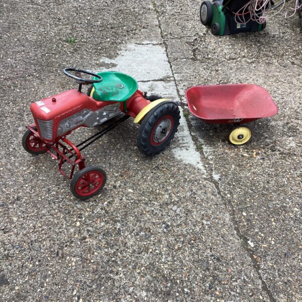 Vintage Triang garden ride-on tractor with trailer in a garden setting.
