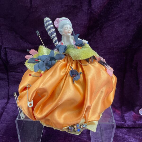 Antique bisque half doll pincushion with silk covering.