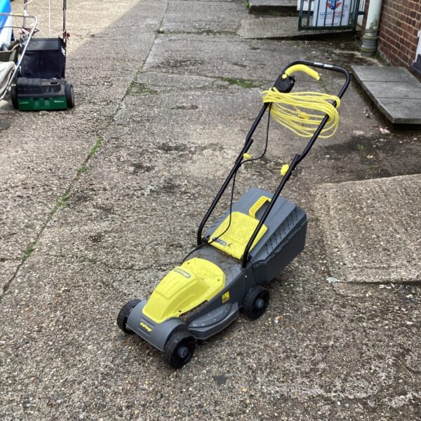 Yellow and black Challenge electric lawn mower in a garden setting.