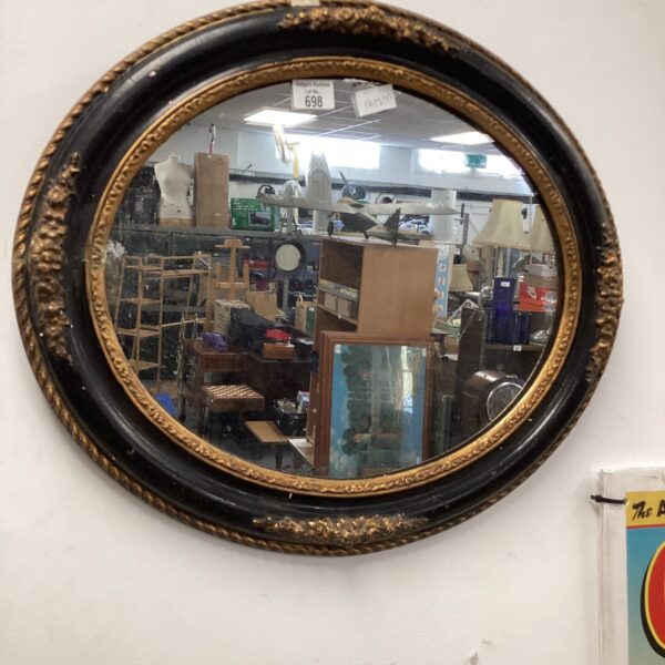 Ornate Victorian oval mirror with black and gilt frame.