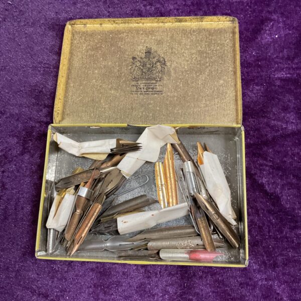 Vintage tin filled with assorted steel dip pen nibs.