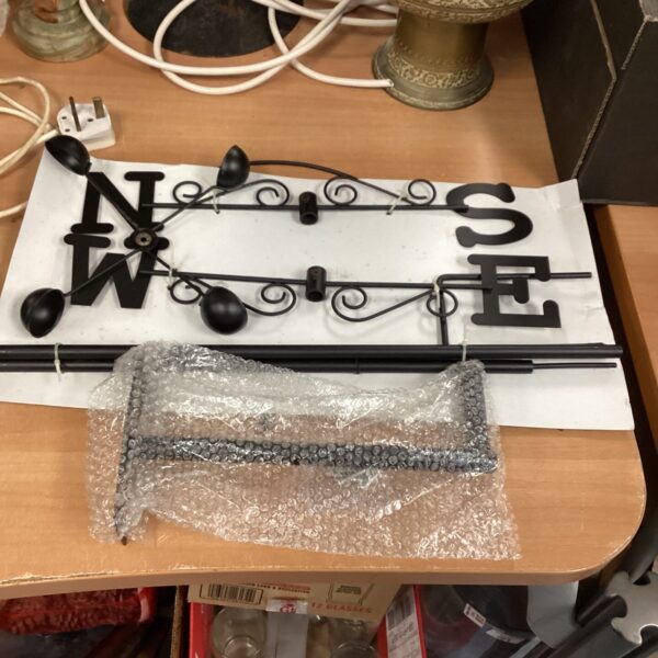 Black metal weather vane with ornate directional arrow.