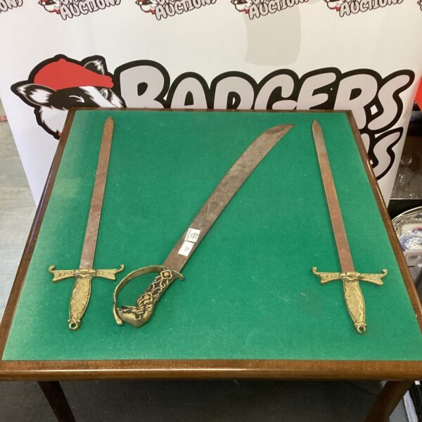 Three decorative swords with ornate brass handles for display and collection.