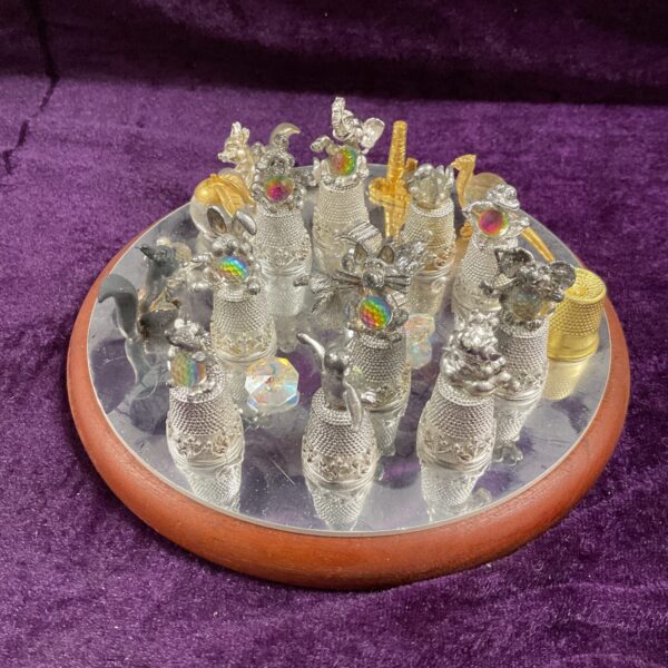 Collectible thimble display with crystal animal figurines on a mirror.