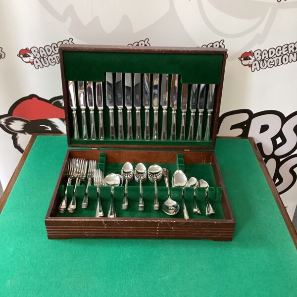 Open silver canteen set with vintage cutlery inside wooden box.