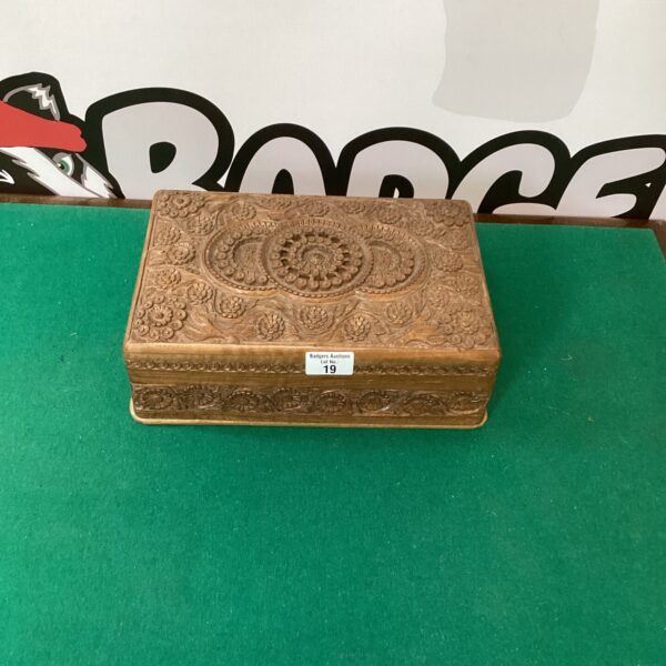 Front view of a vintage carved sandalwood box with velvet lining.