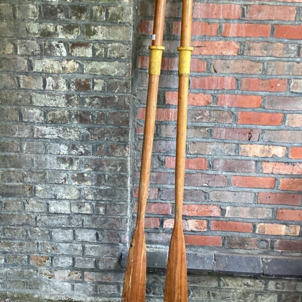 Pair of vintage wooden rowing oars, showing wear and patina.