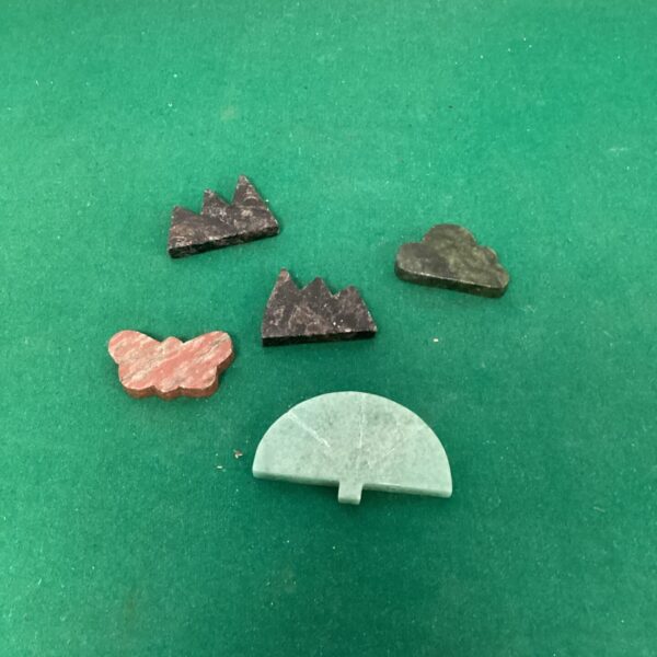 Selection of hand-carved semi-precious stone carvings on a dark surface.