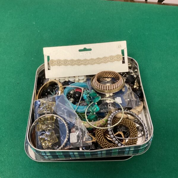 Assorted costume jewellery in a decorative tin.