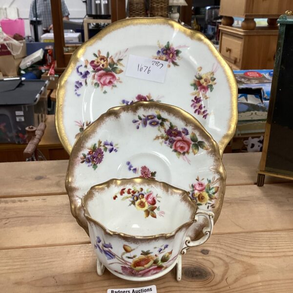 Antique floral cup and saucer on a wooden surface.