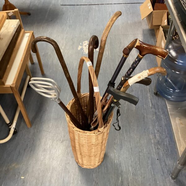 Wicker basket filled with a collection of vintage walking sticks.